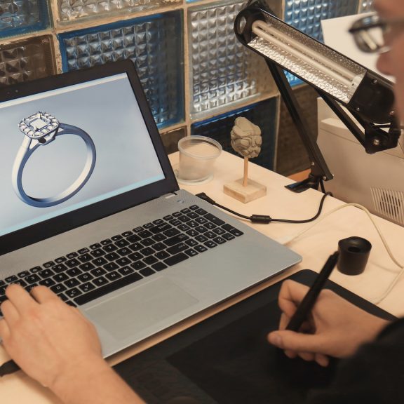Jewelry designer working on laptop, closeup